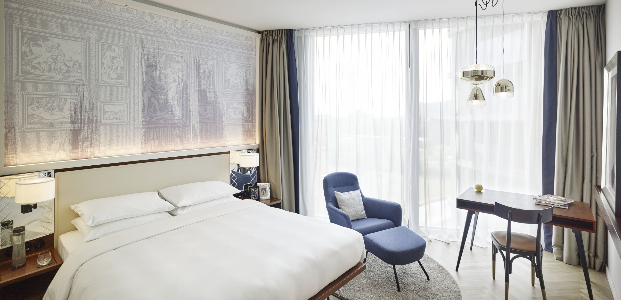 A king bedroom with floor-to-ceiling windows, a desk and a reading chair